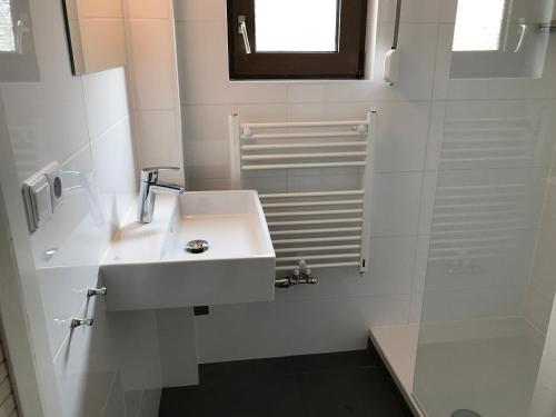 a white bathroom with a sink and a shower at Heerlijk Dijkhuisje in Paal in Graauw