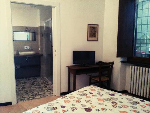 ein Schlafzimmer mit einem Bett und einem Schreibtisch sowie ein Badezimmer in der Unterkunft Oddi21 B&B in Albenga