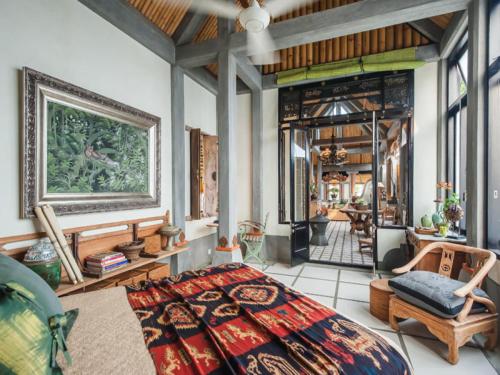 a bedroom with a large bed and chairs in it at Maruti Lane Villa in Ubud