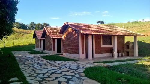 2 pequeñas casas de ladrillo con una pasarela de piedra en Chales Jeitinho Mineiro, en São Thomé das Letras