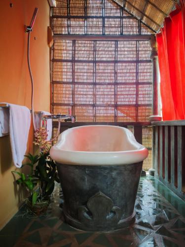 a bath tub in a bathroom with a window at Maruti Lane Villa in Ubud