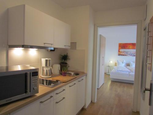 a kitchen with a microwave and a room with a bed at AMENITY-Garden-Apartments in Munich