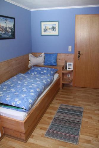 a bedroom with a bed with blue walls and a door at Pension Mühlbauer in Lam