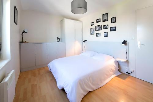 a white bedroom with a white bed and a wooden floor at Ocean Apartment in Saint Malo