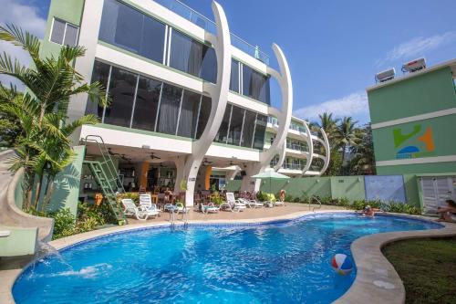 a hotel with a swimming pool in front of a building at Room2Board Hostel and Surf School in Jacó