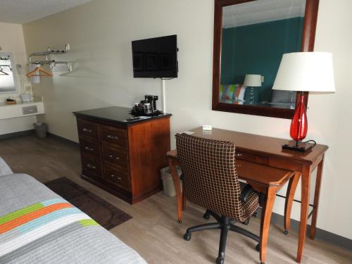 een slaapkamer met een bureau met een lamp en een spiegel bij Edelweiss Inn in Eureka Springs