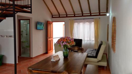 una sala de estar con un jarrón de flores sobre una mesa en Apartahotel La Gran Familia, en Villa de Leyva