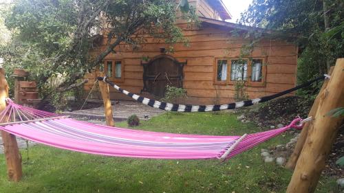 a hammock in front of a log cabin at Vientos de Chauquen in Panguipulli