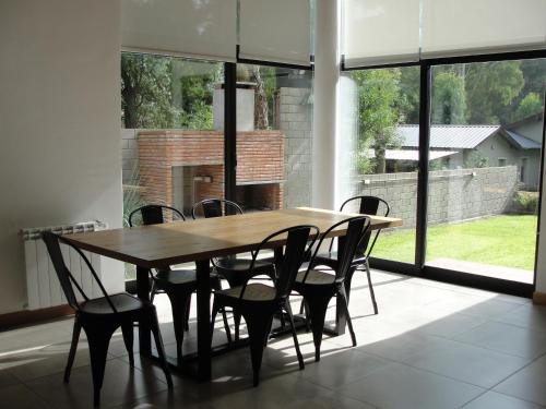 una mesa de madera y sillas en una habitación con ventanas en Casa Huarpes en Mar del Plata