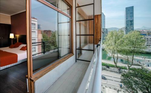 een balkon met een bed en uitzicht op de stad bij Hotel Conde Duque Bilbao in Bilbao