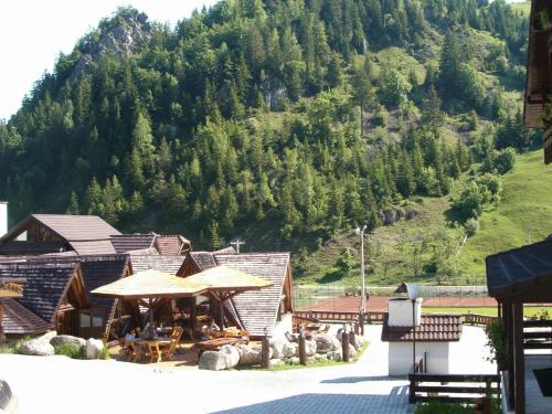 a resort with tables and umbrellas in front of a mountain at Resort Cheile Gradistei Moieciu in Moieciu de Sus