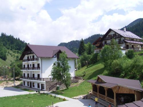 a large white building on a hill with houses at Resort Cheile Gradistei Moieciu in Moieciu de Sus