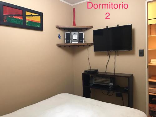Condominio Matta Torre 1 في تيموكو: غرفة نوم بسرير وتلفزيون على جدار