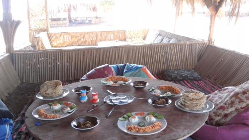 a wooden table with plates of food on it at SakraTah Camp - eco friendly in Taba