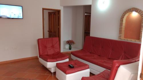 a waiting room with red chairs and a couch at Apartahotel La Gran Familia in Villa de Leyva