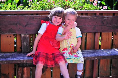 two little girls sitting on a wooden bench at Planatscherhof in Barbiano