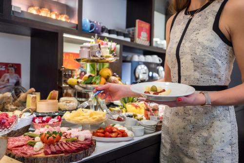 a woman holding a plate of food at a buffet at Boutique Hotel NI-MO in Zürich