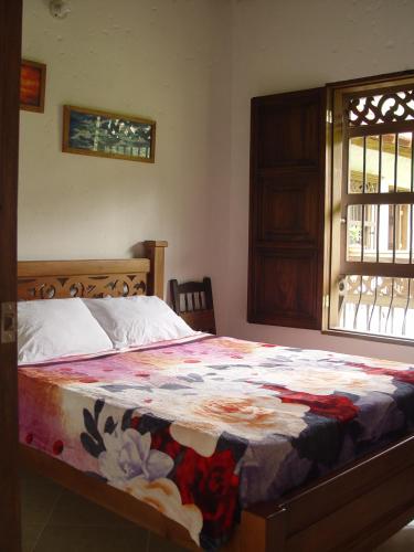 a bedroom with a bed with a colorful quilt on it at Casa Hotel Portón Campestre in Jardin