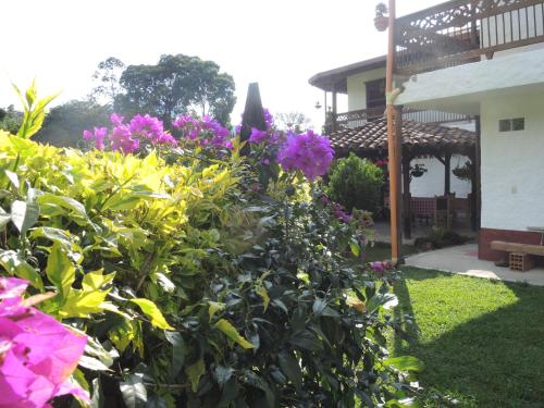 a bush with pink flowers in front of a house at Casa Hotel Portón Campestre in Jardin