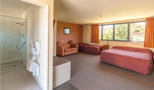 um quarto com uma cama e uma casa de banho com um chuveiro em Waterfront motel em Blenheim