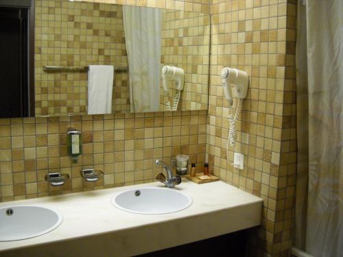 ein Badezimmer mit zwei Waschbecken und einem Telefon an der Wand in der Unterkunft Hôtel Le National in Delémont