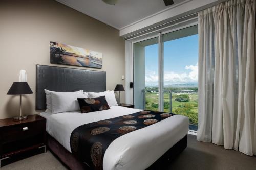 a bedroom with a large bed and a large window at Central Holborn Apartments in Townsville
