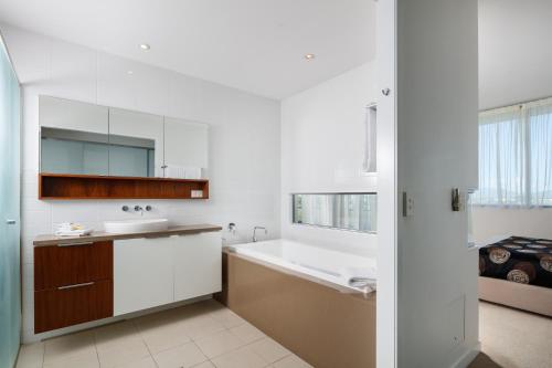 Central Islington Apartments في تاونزفيل: حمام أبيض مع حوض ومغسلة