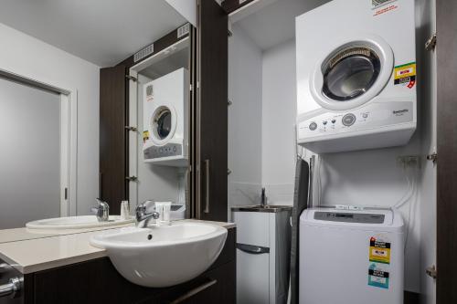 a bathroom with a sink and a washer and dryer at Central Kensington Apartments in Townsville