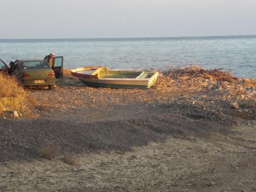 a boat and a car on a beach next to the water at Esperides Hotel in Myrtos