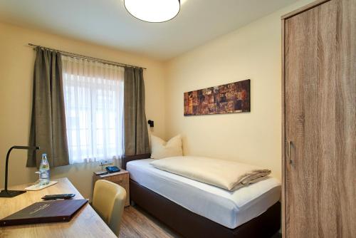 a bedroom with a bed and a desk and a window at Gasthof Gigl in Neustadt an der Donau