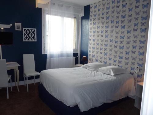 a bedroom with a white bed and a window at Hôtel Patton in Avranches