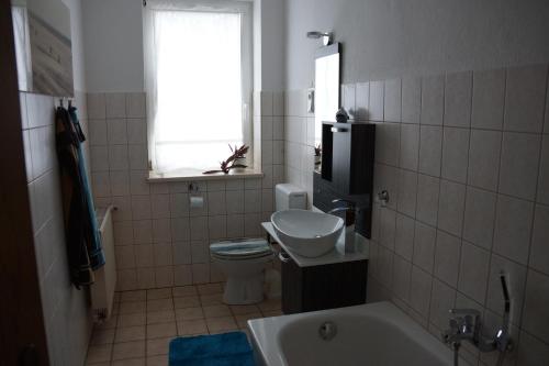 a bathroom with a toilet and a sink and a tub at Ferienwohnung Regina in Mühlhausen