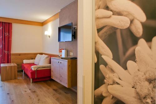 a living room with a red couch and a television at Hotel Truyenhof in Ried im Oberinntal