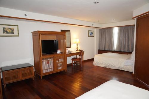 a bedroom with a bed and a desk with a television at Wonderland Private Chalet at Port Dickson in Port Dickson