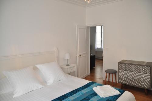 a white bedroom with a bed and a table and a stool at Résidence du Cygne - Swan Residence - Paris centre in Paris