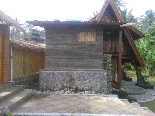 a small house with a stone wall and a balcony at Uma Nirmala Aling-Aling in Singaraja