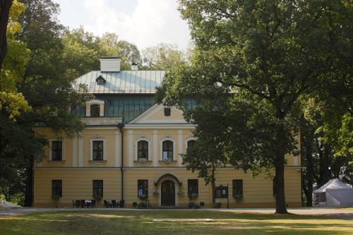 a large yellow house with a blue roof at Palac w Rybnej in Rybna