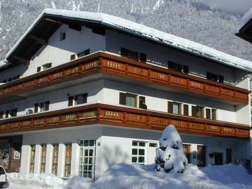 a large building with snow on the ground in front of it at Haus Alpenrose in Obertraun