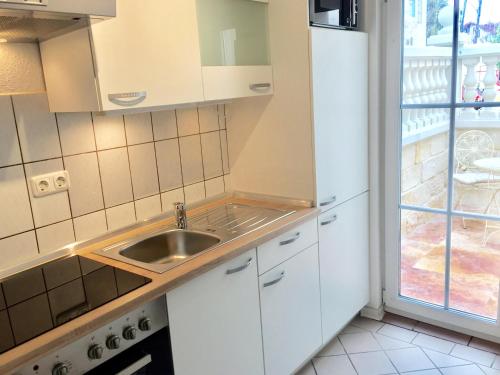 a kitchen with white cabinets and a sink at Wilsmann Apartmentvermietung in Hövelhof