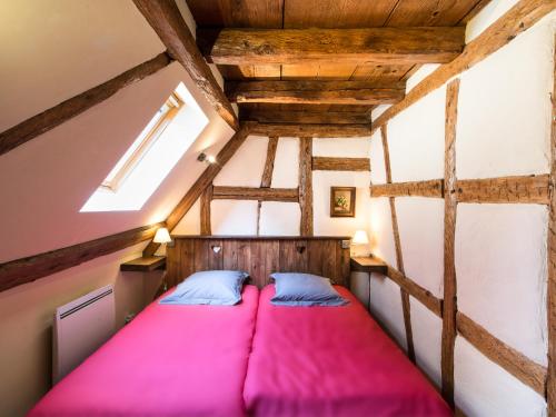 um quarto com uma cama rosa no sótão em Gîtes Strengbach em Ribeauvillé