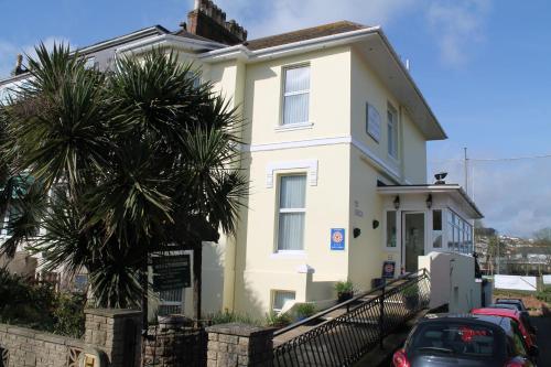 a white house with a palm tree in front of it at The Ashleigh in Paignton
