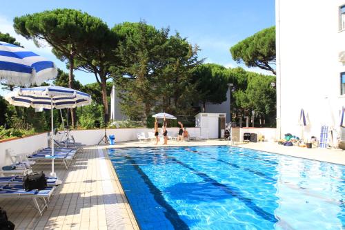 ein Pool mit Stühlen und Sonnenschirmen sowie Menschen im Wasser in der Unterkunft G&D Hotel Deanna Golf in Milano Marittima