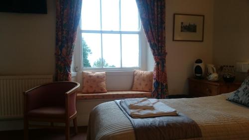 a bedroom with a bed and a window with a chair at The Silverdale Hotel in Silverdale