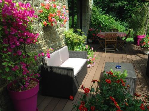 a patio with flowers and a chair and a table at Chambres d'hôtes Le Bas Rassinoux in Saint-Ouen-des-Alleux