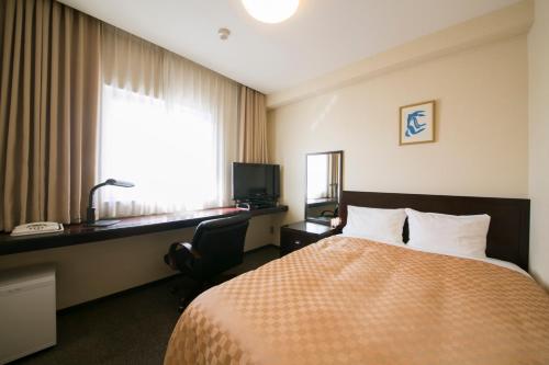 a hotel room with a bed and a desk and a window at Hotel nanvan Yaizu in Yaizu