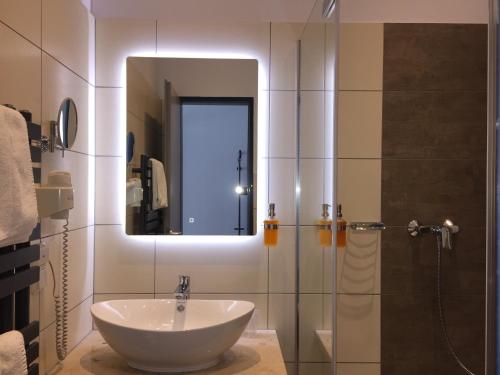 a bathroom with a sink and a shower with a mirror at Median Hotel Garni in Wernigerode