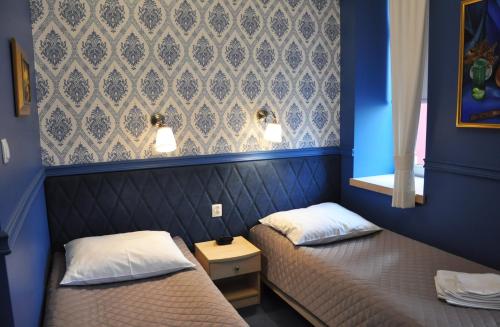two beds in a room with blue walls at Willa Impresja Hotel i Restauracja in Pabianice