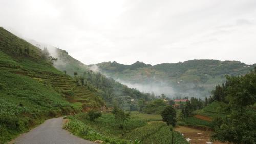 a winding road on a mountain with green hills at Huy Trung Homestay in Bắc Hà