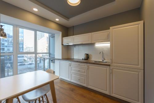 a kitchen with white cabinets and a table and a window at Partner Guest House in Kyiv
