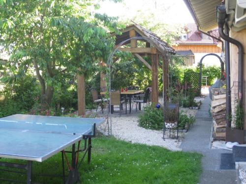 a ping pong table in a garden with an arbor at Ferienwohnung Breu in Arnbruck